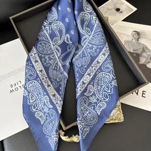 Détail d'un foulard en soie bleu marine à motifs paisley sur un plateau élégant