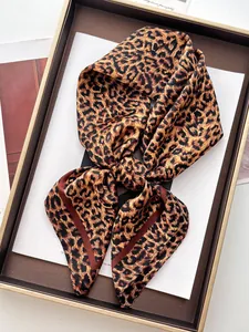 Dettaglio di una sciarpa in seta leopardata piegata in una scatola regalo con bordo dorato