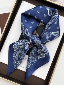 Détail d'un foulard en soie bleu marine à motifs paisley noué dans un coffret