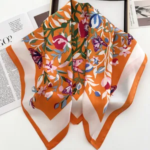 Détail d'un foulard en soie à fleurs et papillons posé sur un magazine de mode