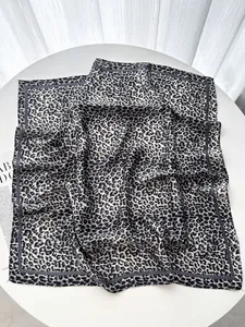 Dettaglio della trama di un foulard in seta leopardata su un tavolo bianco pulito