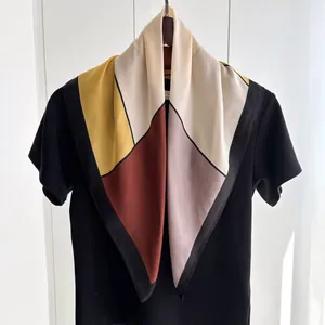 Détail d'un foulard carré en soie synthétique avec imprimé géométrique et drapé élégant