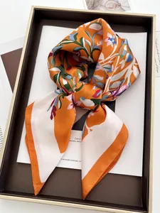 Détail d'un foulard en soie à fleurs avec ourlet orange sur un plateau rétro
