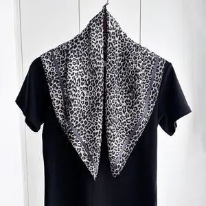Dettaglio del foulard in seta con stampa leopardata e motivi classici neri e bianchi