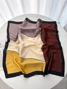 Détail d'un foulard en satin de soie avec blocs de couleurs géométriques bordeaux et jaune