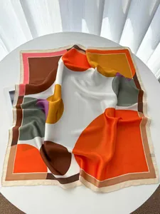 Vue détaillée d'un foulard en soie aux motifs géométriques sur une table blanche