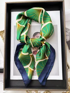 Dettaglio foulard in seta a righe verde e giallo con bordo blu scuro su vassoio