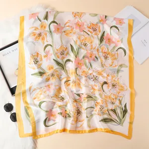 Detailed close-up of a floral silk scarf with tulip prints and bright yellow borders