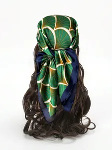 Dettaglio di un foulard di seta verde indossato come fascia per capelli lunghi castani