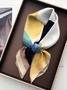 Gros plan d'un foulard en soie géométrique aux couleurs contrastées sur un plateau