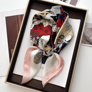 Dettaglio di un foulard in seta con stampa di gatti, presentato in una confezione regalo