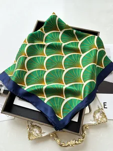 Dettaglio del foulard in seta con motivi a ginkgo verdi e bordi blu navy raffinati