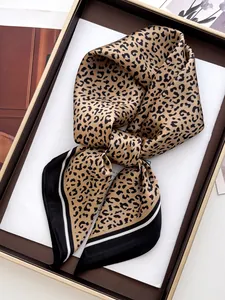 Dettaglio di un foulard in seta con stampa leopardata e strisce in una scatola regalo