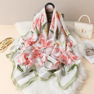 Detail of satin floral scarf with pink tulips on white faux fur and stylish handbags