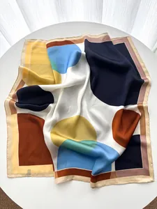 Détail d'un foulard carré en soie avec motifs géométriques abstraits et bords roulés
