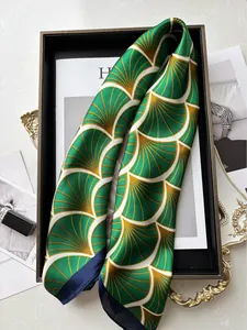Dettaglio di un foulard in seta con motivi a ventaglio verdi e oro su un vassoio decorativo