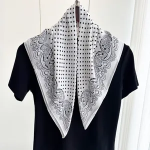 Dettaglio di un foulard di seta paisley bianco e nero con pois e consistenza satinata