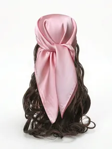 Gros plan détaillé d'un carré de soie satinée rose noué élégamment sur des cheveux sombres