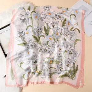 Close-up of pink silk square scarf featuring delicate tulip floral patterns and soft texture