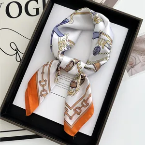 Satin silk scarf with chain print and orange border displayed on a fashion magazine