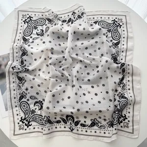 Detailed view of lightweight ivory paisley silk scarf with elegant hemmed edges on a table