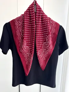 Dettaglio di sciarpa rossa a pois in cotone e lino con motivo paisley su top nero