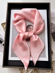 Vue détaillée d'un foulard carré en satin rose noué avec une texture perle lisse