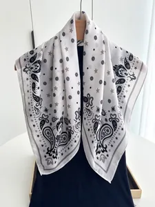 Detail of white cotton linen scarf with black paisley and star patterns on a hanger