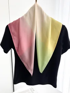 Détail d'un carré de soie au dégradé pastel drapé sur un haut noir élégant et doux
