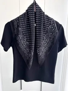 Dettaglio di sciarpa in cotone e lino con pois bianchi e neri e motivi floreali paisley
