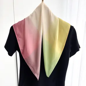 Gros plan d'un foulard carré en satin léger avec dégradés de rose doux et vert menthe