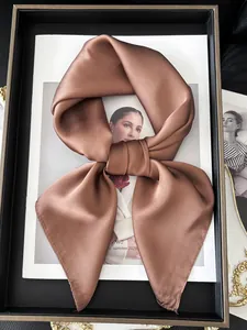 Carré de soie satiné marron noué en ruban sur un plateau décoratif avec magazine