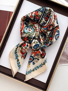 Détail d'un foulard en soie à imprimé floral et motifs folk noué sur un plateau chic