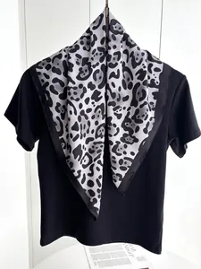Dettaglio di un foulard di seta leopardato abbinato a una maglietta nera alla moda