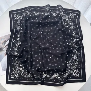 Detailed close-up of a black square scarf featuring white paisley and star patterns