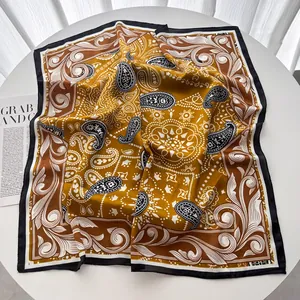 Dettaglio di foulard in seta giallo con motivo paisley su uno sfondo bianco minimale
