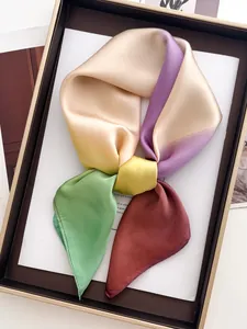 Détail d'un foulard en satin soyeux dégradé noué en nœud dans un coffret de luxe