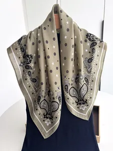 Detail of olive green paisley scarf featuring starry patterns and fine twill fabric texture