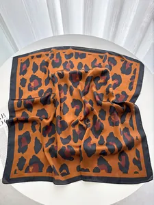 Dettaglio del foulard in seta con stampa leopardata e bordi neri su supporto elegante