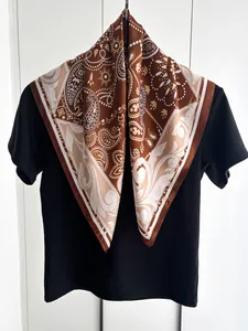 Dettaglio del foulard di seta marrone con motivo paisley abbinato a una maglietta nera