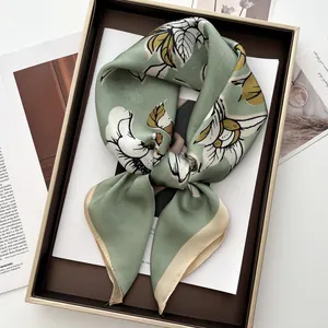 Sage green silk scarf featuring white magnolia floral prints and a beige rolled hem