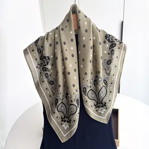 Detail of olive green paisley square scarf with star patterns on a wooden hanger