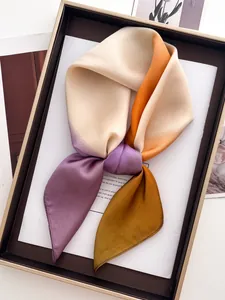 Gros plan du foulard en soie noué montrant un dégradé d'orange, violet et jaune