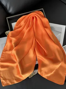 Gros plan d'un foulard en satin orange avec des bords roulés et texture soyeuse