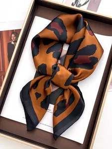Dettaglio foulard in seta leopardata con bordo nero su un vassoio vintage in pelle