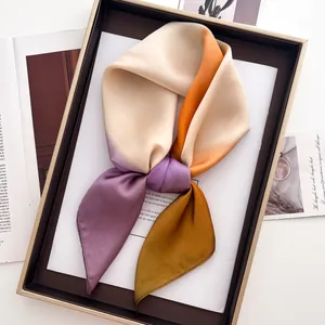 Vue détaillée d'un foulard en soie dégradé beige et orange plié dans un coffret cadeau chic