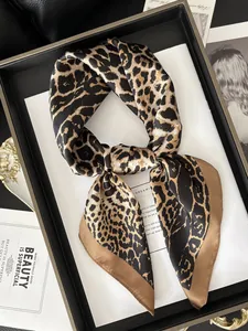 Macro shot of a leopard print silk scarf with brown border neatly tied in a black tray