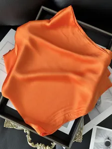 Gros plan d'un foulard carré en satin orange vif avec un lustre soyeux