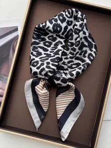 Gros plan d'un foulard en soie léopard et rayures sur un plateau de présentation