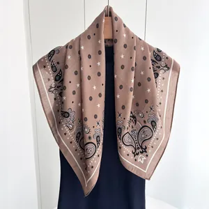 Detail of a brown paisley square silk scarf with vintage patterns on a wooden hanger